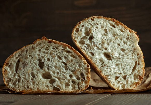 Bread, traditional sourdough bread cut into slices on a rustic wooden background. Concept of traditional leavened bread baking methods. Healthy food.